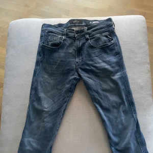 Replay Anbass jeans blå, stl 31 - Snygga Replay Anbass jeans i klassisk blå tvätt med lätt slitning och raka ben. Jeansen har fem fickor, tydliga sömmar och en bekväm passform. Perfekta för dig som gillar en stilren och modern look.