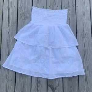 Vit tup klänning från Gina Tricot - Supersöt vit tup klänning från Gina Tricot med smock på bröstet och dubbla volanger. Den är helt ny men utan prislapp.
