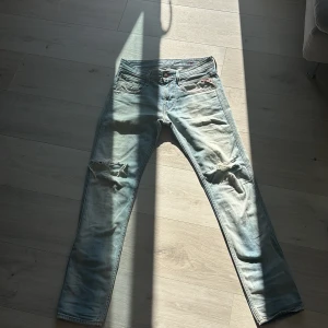 Replay ljusblå slitna jeans 29/32 - Säljer ett par ljusblå jeans från Replay med snygga slitningar och hål på båda knäna. Klassisk femficksmodell med raka ben och normal passform. Jeansen har en cool tvättad look och är tillverkade i bomull.