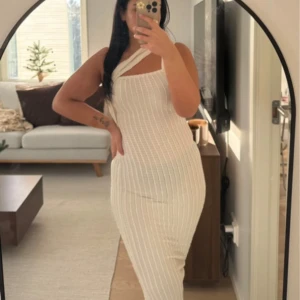 Vit ribbad långklänning oneshoulder - Supersnygg vit långklänning med ribbad struktur och oneshoulder-design. Klänningen sitter tight och har en modern, stilren look som passar perfekt när du vill sticka ut lite extra.