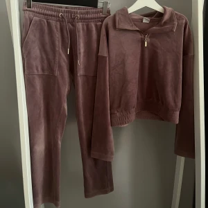 Lila mjukisbyxor i velour - Fint mjukis sett! Supermjuka lila mjukisbyxor i velour med bred resår och snörning i midjan. Byxorna har raka ben och stora fickor framtill. Perfekta för chill eller myskvällar. Matchande tröja med zip i samma material. 70kr stycket eller 120 för hela setet