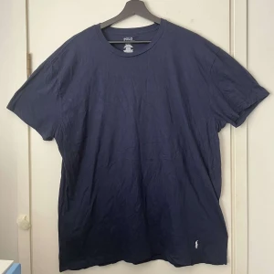 Marinblå t-shirt från Polo Ralph Lauren - Snygg marinblå t-shirt från Polo Ralph Lauren i klassisk passform. Tillverkad i mjuk bomull och prydd med den ikoniska broderade loggan i vitt nedtill. Perfekt basic-plagg med rund hals och korta ärmar.
