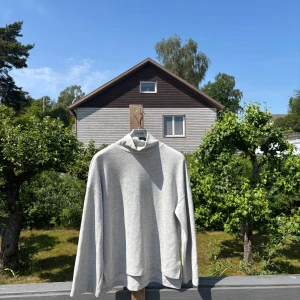 Ljusgrå polotröja från Gina Tricot - Säljer en stilren ljusgrå polotröja från Gina Tricot i mjuk bomullsblandning. Tröjan har en hög krage och långa ärmar, perfekt för lager-på-lager. Enkel och clean look som funkar till allt. Passformen är normal och materialet är ribbat för extra komfort.