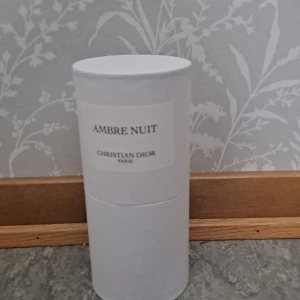 Ambre Nuit parfym från Dior - Ambre Nuit från Christian Dior är en lyxig parfym i en stilren, cylindrisk glasflaska med svart lock. Doften kommer i en elegant vit kartongtub med minimalistisk etikett. Parfymen har en gyllene bärnstensfärg som ger exklusiv känsla.