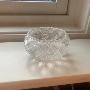 Glas skål  - Bilderna visar en rund, dekorativ glasskål med slipat mönster och räfflad kant. Skålen har ett klassiskt, vintage-inspirerat utseende och passar perfekt som inredningsdetalj eller för att servera snacks och godis. Perfekt för dig som gillar retrostil och vill ge ditt rum en unik touch. Perfekt o lägga smycken i också mm 