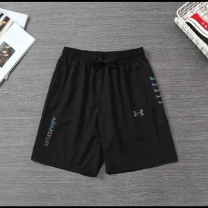 Svarta träningsshorts från Under Armour - Svarta träningsshorts från Under Armour med elastisk midja och snörning. Shortsen har regnbågsfärgad logga och textdetaljer på ena benet. Perfekta för gymmet eller löprundan, tillverkade i lätt och snabbtorkande syntetmaterial.