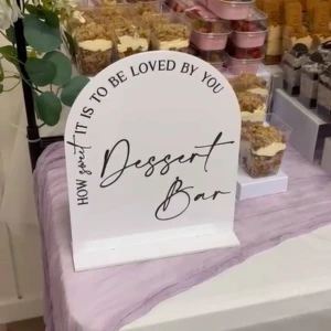 Dessert Bar skylt - En dekorativ skylt med texten 'How sweet it is to be loved by you - Dessert Bar'. Perfekt för att skapa en inbjudande dessertbuffé på fester eller event. Skylten är 25,4 cm hög och 20,3 cm bred, stilren och passar alla tillfällen där du vill bjuda på sötsaker.