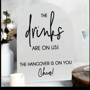 Bar skylt - Bilden visare en dekorativ skylt med texten: 'The drinks are on us! The hangover is on you. Cheers!'. Denna skylt är perfekt för att piffa upp dryckes bordet lite. Stolek 