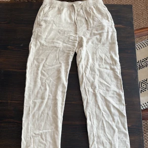 Beiga linnebyxor från Only & Sons - Snygga beiga linnebyxor från Only & Sons med avslappnad passform och elastisk midja med snörning. Perfekta för varma dagar, tillverkade i svalt linnematerial. Klassisk rak modell med fickor i sidorna och baktill.