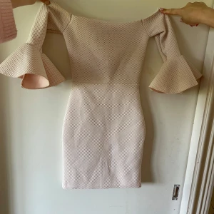 Ljusrosa kortklänning med trumpetärm - Superfin ljusrosa kortklänning med offshoulder och trumpetärmar. Klänningen har ett diskret rutmönster och passar perfekt nu till sommaren. Står att det är storlek M men skulle uppskatta till storlek xs då den är liten i storleken🌸