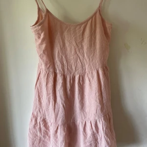 Ljusrosa sommarklänning från H&M - Supersöt ljusrosa klänning från H&M med tunna axelband och volangig kjol. Tillverkad i mjuk bomull med lätt skrynklig struktur. Perfekt för varma dagar nu i sommar. Storlek 34. Säljs för att den inte passar. Ställ frågor🌸