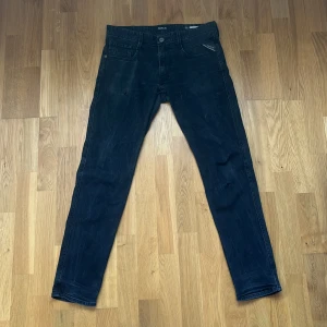 Svarta Replay anbass jeansbyxor W32 L32 - Snygga svarta jeans från Replay med klassisk femficksdesign och smal passform. Jeansen har låg midja och är tillverkade i stretchigt bomullsmaterial för extra komfort. Perfekta för dig som gillar en stilren och modern look.