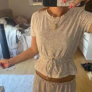 Prickig topp  från Zara - Supersöt vit topp från Zara med svarta prickar, rund hals och korta ärmar. Midjan har smock och knytband.  Super gullig och kommer inte till andvändning.