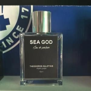 Sea God Eau de Parfum 50ml - Sea God Eau de Parfum från Theodoros Kalotinis är en stilren parfym i en transparent, fyrkantig glasflaska med silverfärgad metallkork. Flaskan har en svart etikett med vit text och rymmer 50 ml. Doften utstrålar exklusivitet och modern känsla. Det är ungefär 45-46 ml kvar