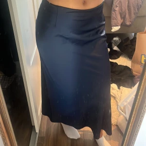 Mörkblå satinkjol - Säljer en midikjol i satin från Bikbok. Kjolen är i färgen mörkblå och har slits på ena benet. Storlek S. Knappt använd🩷