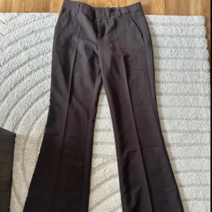 Bruna bootcut kostymbyxor BikBok - Snygga svarta kostymbyxor från BikBok i bootcut-modell. Byxorna har hög midja, klassiska fickor och är gjorda i ett mjukt material som känns bekvämt hela dagen. Perfekta till en trendig look med sneakers eller klackar.