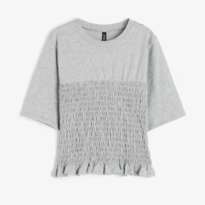 Grå croppad topp med volangkant - Supergullig smockad topp från hm , köpte här på plick och storleken är L men eftersom den formar sig efter figuren så passar den lika bra som en S elr M