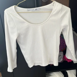 Vit ribbad långärmad topp 157 - Säljer en stilren vit långärmad topp från 157 i storlek M/L. Toppen är ribbad med rund halsringning och har en slim passform som sitter snyggt på kroppen. Perfekt att matcha med jeans eller kjol för en clean look.