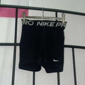 Nike Pro svarta träningstights shorts XS - Svarta Nike Pro Dri-FIT shorts med tight passform och bred resår i midjan med Nike-logga. Perfekta för träning eller sport, tillverkade i ett syntetmaterial som andas och transporterar bort fukt. Klassisk stil med liten vit swoosh på benet. Knappt använda