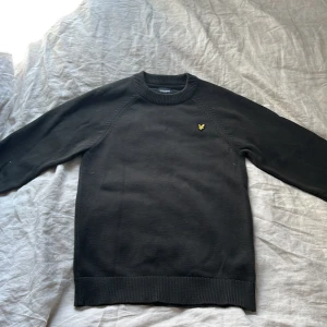 Grön stickad tröja Lyle & Scott - Grön stickad tröja från Lyle & Scott med klassisk rund hals och gul logga på bröstet. Tröjan har ribbade muddar vid ärmslut och nederkant, perfekt för dig som gillar en clean och stilren look.          Pris kan diskuteras!!
