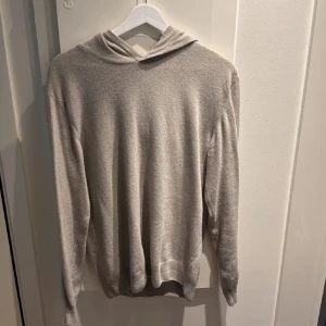 Beige hoodie i mjukt material, Oscar Jacobson  - En stilren beige hoodie med lång ärm och huva. Tröjan är i ett mjukt och skönt material, perfekt för chill dagar. Enkel design utan tryck eller mönster, passar dig som gillar en clean look.