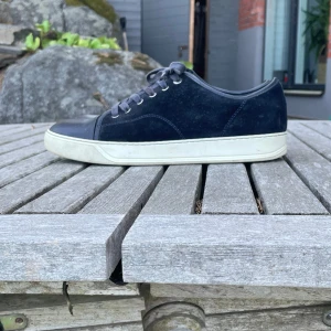 Navy blue sneakers från Lanvin i mocka - Stilrena navy blue sneakers från Lanvin med ovandel i mocka och detaljer i skinn. Perfekt för dig som vill vara stilig på både fina engagemang men även lite lugnare tillfällen. Skriv om ni har frågor😊