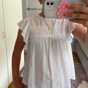 Vit blus med spets och volangärmar - Supersöt vit blus med broderade detaljer och spetsband över bröstet. Sparsamt använd och inga defekter!!💓💓