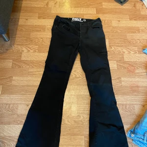 Svarta bootcut jeans från ONLY - Svarta jeans från ONLY med bootcut-modell och klassisk femficksdesign. Jeansen har normal passform och är tillverkade i ett stretchigt denimtyg som sitter snyggt över höfterna och släpper ut över benen. Perfekta för dig som gillar en tidlös look.