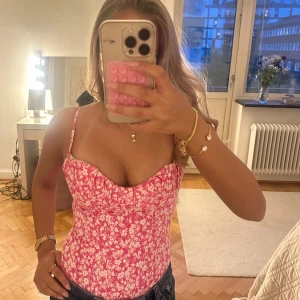 Rosa blommig body/korsett  - Säljer en söt rosa linnetopp med vitt blommönster och smala axelband. Toppen är croppad och har en figurnära passform, perfekt för varma dagar. Säljer då jag har två❤️
