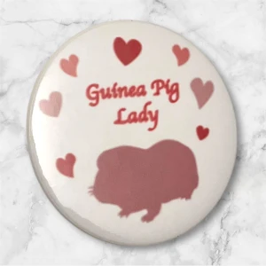 Pin Guinea Pig Lady Marsvin Badge - Söt pin med texten ”Guinea Pig Lady” och siluetten av marsvin och hjärtan i rosa nyanser. Ca 4,4 cm i diameter. Perfekt för den som älskar marsvin 💕 