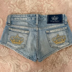 Jeansshorts Victoria Beckham krona - Snygga ljusblå jeansshorts från Victoria Beckham med ikoniska guldfärgade kronbroderier och strass på bakfickorna! 