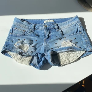 Lågmidjade jeansshorts - Snygga jeansshorts med lågmidja, coola nitar och slitningar framtill, midja 38cm, grenhöjd 17cm🤗❤️