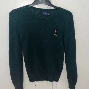 Grön stickad tröja från Polo Ralph Lauren - Säljer en stilren grön stickad tröja från Polo Ralph Lauren med det klassiska broderade logotypen på bröstet. Tröjan har långa ärmar och en rund halsringning. Perfekt för en elegant och avslappnad look. Ralph lauren taggen vid nacken har gått av på en sida men resten av tröjan är i perfekt skick. Tröjan är storlek xs men passar också xxs eller 164