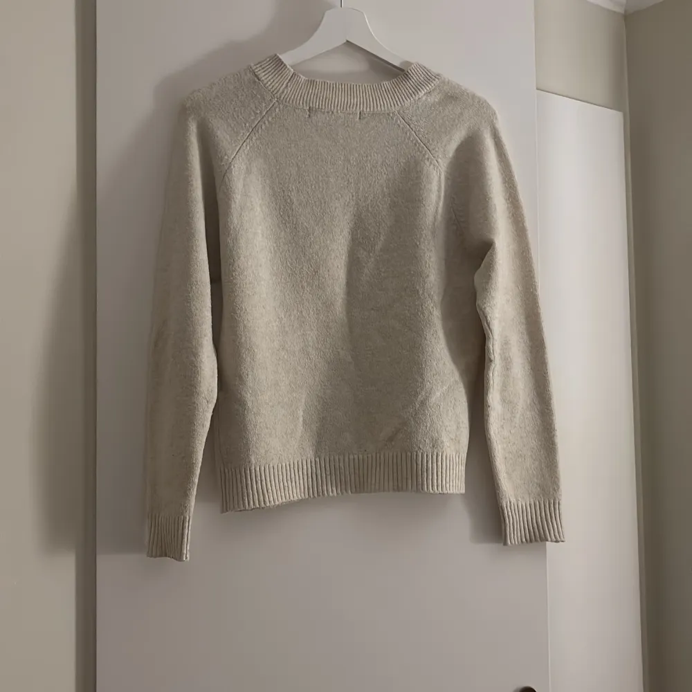 Säljer en mysig beige stickad tröja från Vero Moda. Tröjan har en klassisk design med långa ärmar och ribbade muddar vid ärmslut och nederkant. Perfekt för kyliga dagar!. Neuletakit & Villapaidat.