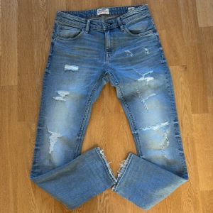 Blå jeans från Crocker - Säljer ett par snygga blå jeans från Crocker med slitna detaljer och en slim passform.strl 28/30 Jeansen har en klassisk femficksdesign och är tillverkade i denim. Perfekta för en avslappnad stil.