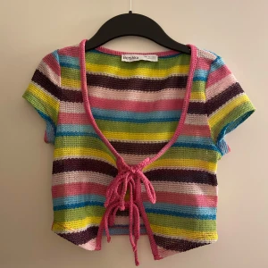 Färgglad randig topp från Bershka - Säljer en färgglad randig topp från Bershka med korta ärmar och knytning framtill. Den är i storlek S och säljs för 40kr.❤️