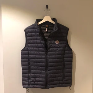 Mörkblå dunväst från Colmar - Snygg mörkblå dunväst från Colmar med dragkedja och rund logotyp på bröstet. Inga defekter. Perfekt för lager-på-lager under kyliga dagar. Västen har en quiltad design och praktiska fickor med dragkedja. Västen är köpt på Boozt.com för 2599kr, vid frågor så är det bara att höra av sig💫
