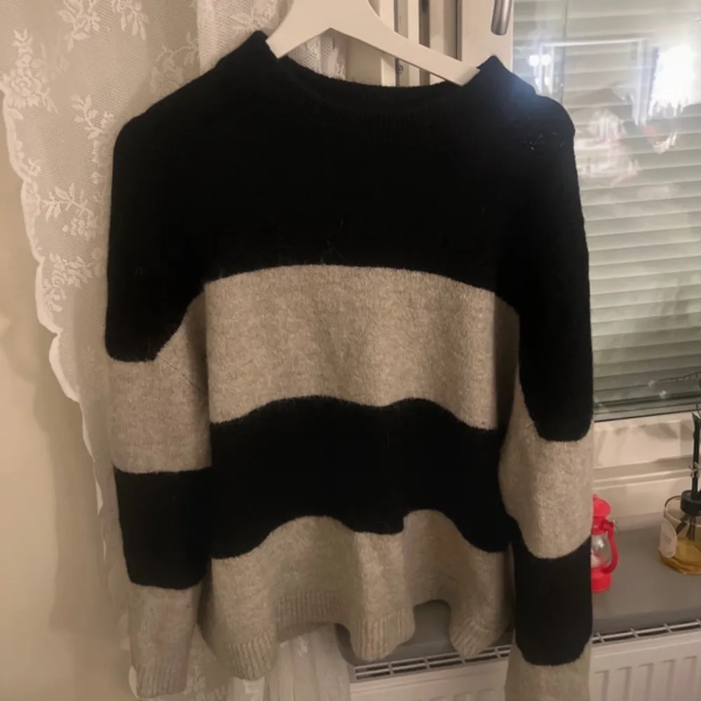 Säljer en mysig stickad tröja från Gina Tricot i svart och grå/brun. Tröjan har ett randigt mönster och långa ärmar. Perfekt för kyliga dagar!. Neuleet.