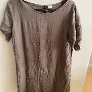 Brun klänning från H&M Divided - Säljer en brun klänning från H&M Divided. Klänningen har en enkel design med korta ärmar och rund hals. Perfekt för en avslappnad stil.