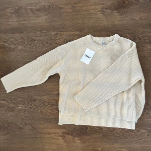 Beige stickad tröja från ONLY - Säljer en snygg beige stickad tröja från ONLY. Den är mjuk och bekväm med en avslappnad passform. Passar bra till både jeans och kjol. Storlek L. Helt ny så säljer för 200kr