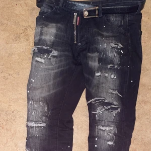 Svarta jeans med slitningar och färgstänk - Snygga svarta jeans med coola slitningar och vita färgstänk. De har en dragkedja och knapp framtill. Perfekta för en ny look, Använd ca 5 gånger