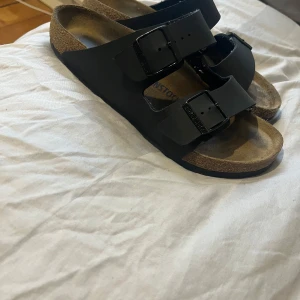 Svarta sandaler från Birkenstock storlek 42 - Säljer ett par klassiska svarta sandaler från Birkenstock. Riktigt sköna enligt mig. Perfekta för sommaren. Tofflorna är i bra skick😃