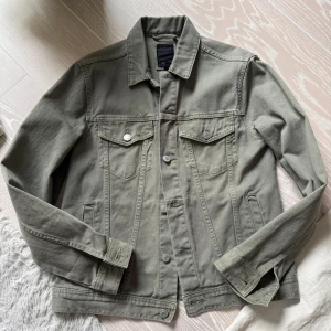 Grön jeansjacka från New Look strl:Small - Snygg grön jeansjacka från New Look med klassisk krage och knappar framtill. Jackan har två bröstfickor med lock och knappar samt två sidofickor. Perfekt för en avslappnad stil.