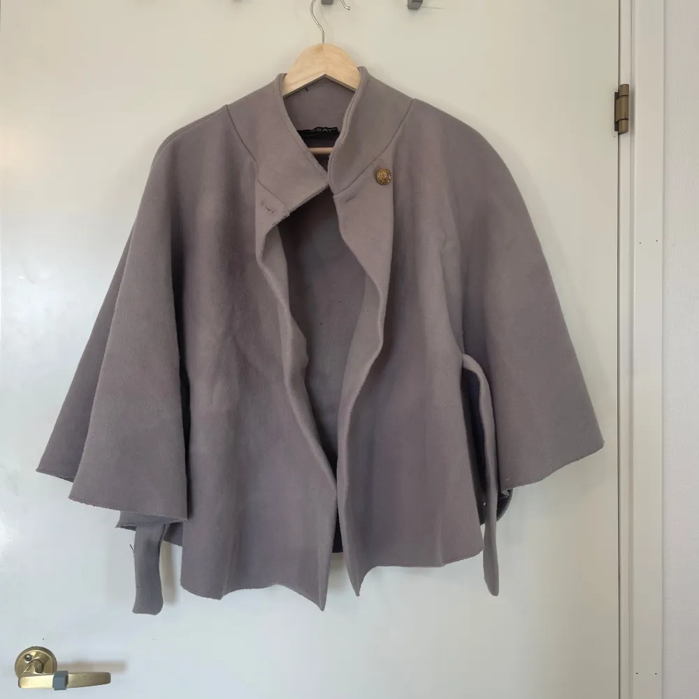 Missäy poncho/kappa i grå. Är lite nopprig och skrynklig. . Takit.
