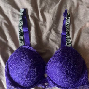 Lila spets-bh från Victoria's Secret - Snygg lila bh från Victoria's Secret med spetsdetaljer och glittriga axelband. Är köp här på Plick och lappen med storlek är ej kvar, men passar mig som är 80 B/C. Endast två stenar som lossnat (se bild)