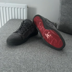 Louboutin  - Snygga svarta sneakers i mocka med en unik röd sula. Skorna har snörning och en stilren design som passar perfekt för en avslappnad look. Insidan är klädd i ett ljust material för extra komfort. Har ej använt dem så mycket dem är i väldigt bra skick. Pris kan diskuteras.