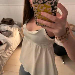 Vit ärmlös topp från 157 - Säljer en söt vit ärmlös topp från 157. Toppen har volangdetaljer vid axelbanden och en luftig passform. Inga defekter