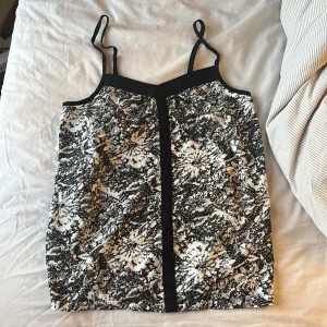 Svartvit mönstrad linnetopp från Vero Moda - Säljer en snygg svartvit mönstrad linnetopp från Vero Moda. Toppen har smala axelband och knappar fram! Storleken är XS men skulle passa S/M också