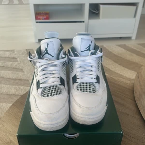 Nike Air Jordans i vitt och grönt - Säljer ett par stilrena Nike Air Jordans i vitt med gröna detaljer. Skorna har klassisk snörning och en ikonisk design med Jumpman-loggan. Perfekta för sneakerheads som vill ha något unikt i sin samling.