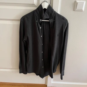 Mörkgrå skjorta från Polo - Säljer en stilren mörkgrå skjorta från Polo Ralph Lauren. Säljer den pågrund av att den är för liten. Cond 9/10 size S. Kan gå ner i pris vid snabb affär vi fler frågor kontakta gärna mig